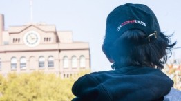 student standing away from the camera with the foundation building in the background