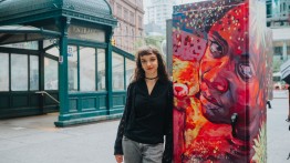 astor place subway stop in background of Juliana standing by her work