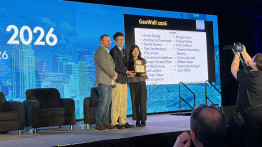 Two students hold an award with a third person