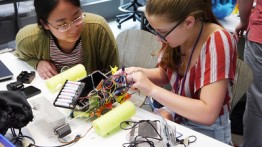 Two students work on assembling an electronics circuit for a remote control vehicle.