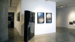 Installation view of Oscar Tuazon’s Black Slab, 2008 (center right) and Afognak (triptych), 2008 (center left)